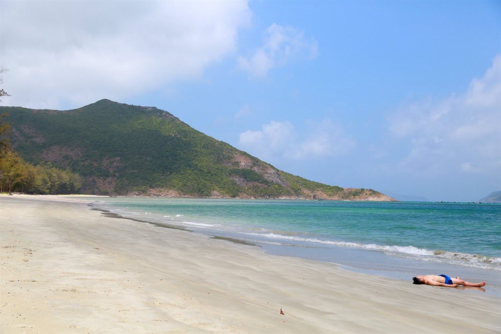 Long quiet beach, turquoise sea and green mountain on Côn Đảo